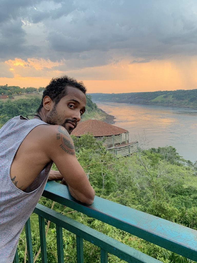 Josue leaning on a railing over the river at Las Tres Fronteras at sunset